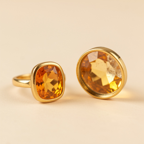 Bague ornée d’une citrine dorée placée à côté d’une pierre de citrine naturelle observée à la loupe.