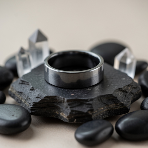 Bague en hématite polie posée sur une pierre sombre, évoquant la force, l’ancrage et l’équilibre.